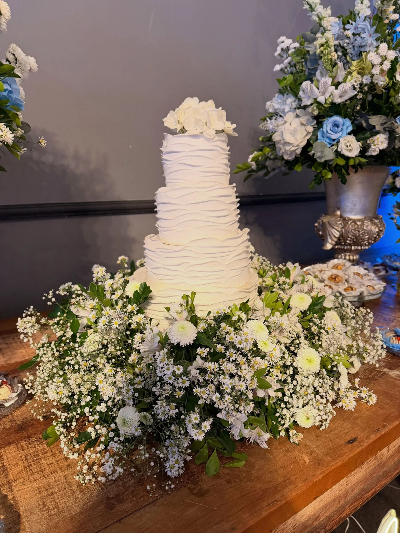 Bolo de casamento branco em mesa decorada com flores